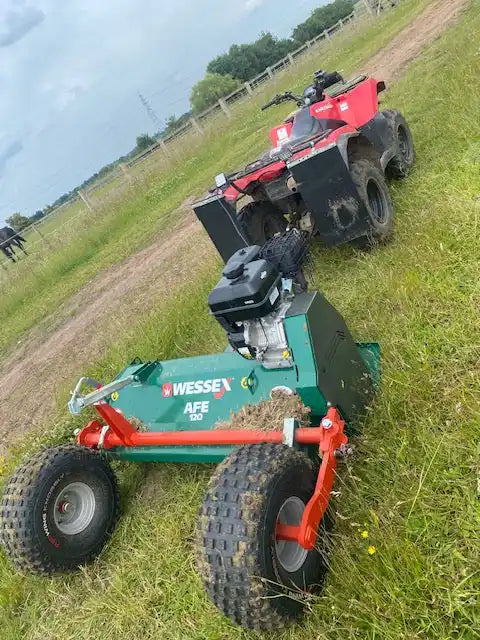 Red ATV towing a green mower.