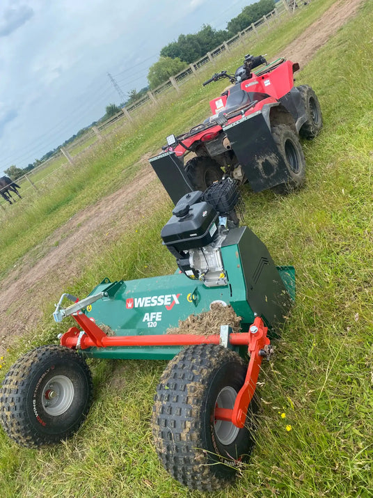 Red ATV towing a green mower.